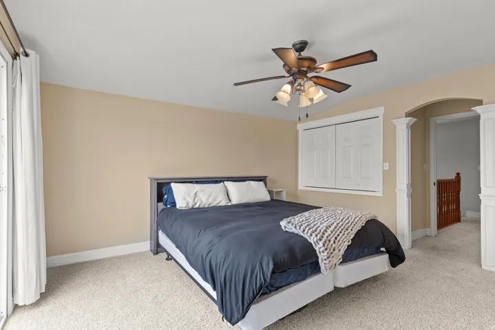 Spacious bedroom featuring neutral wall finishes, carpeted flooring, and abundant natural light from large windows