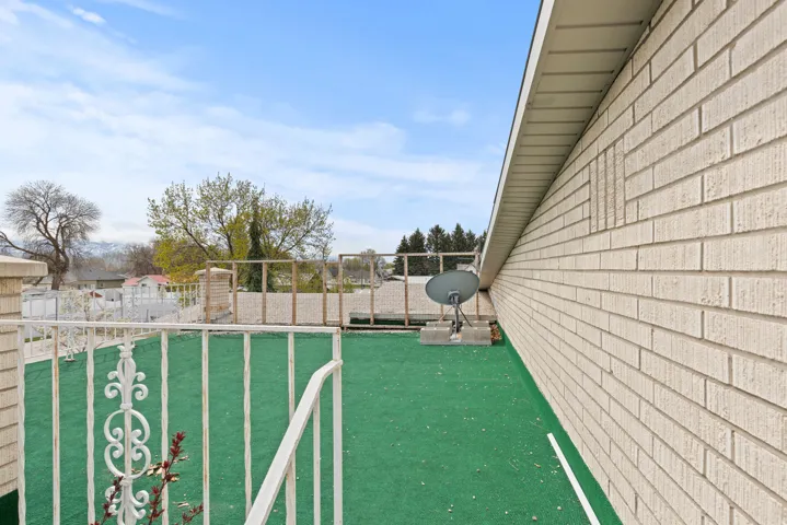 Outdoor patio space featuring green turf flooring and white metal railing