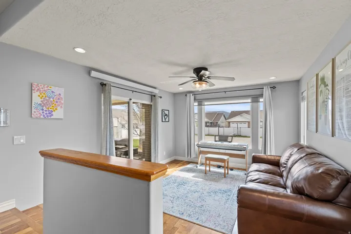 Bright, open living space featuring a wood-finish bar with gray cabinetry, ceiling fan, and recessed lighting