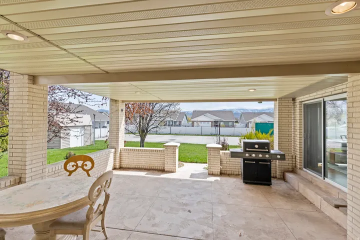 Covered patio featuring a concrete surface, brick construction, and integrated outdoor kitchen with built-in grill