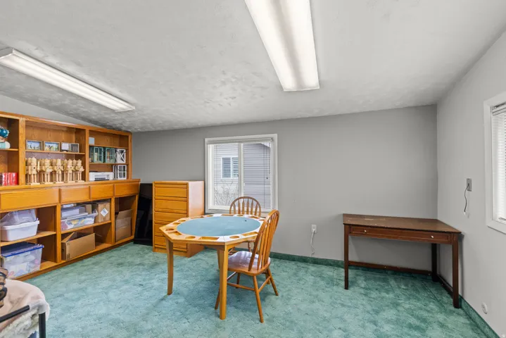 Versatile Recreation Room featuring built-in wooden cabinetry and shelving, green tile flooring, recessed and linear ceiling lighting, and flexible space suitable for hobbies, games, or creative pursuits