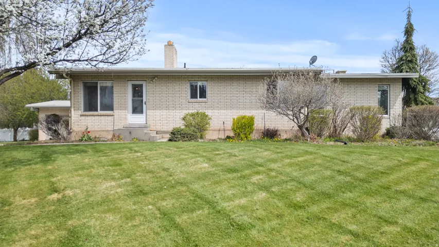 Brick exterior ranch-style home featuring a prominent front lawn