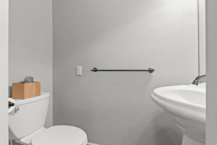 Clean and functional bathroom featuring dual pedestal sinks, white porcelain fixtures, and brushed black hardware