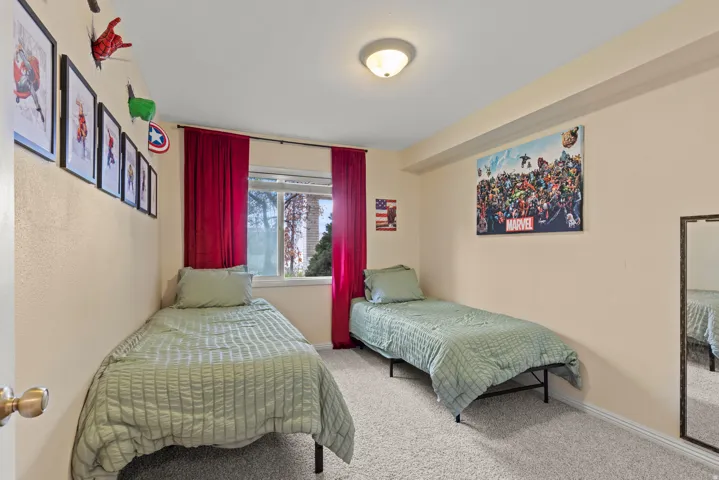 Carpeted room featuring a window with red drapes, a ceiling-mounted light fixture, and light-toned walls