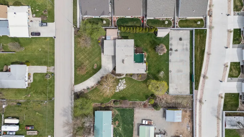 Aerial overview showcasing the property with a private pool, extensive lawn areas, mature trees, and a curved driveway