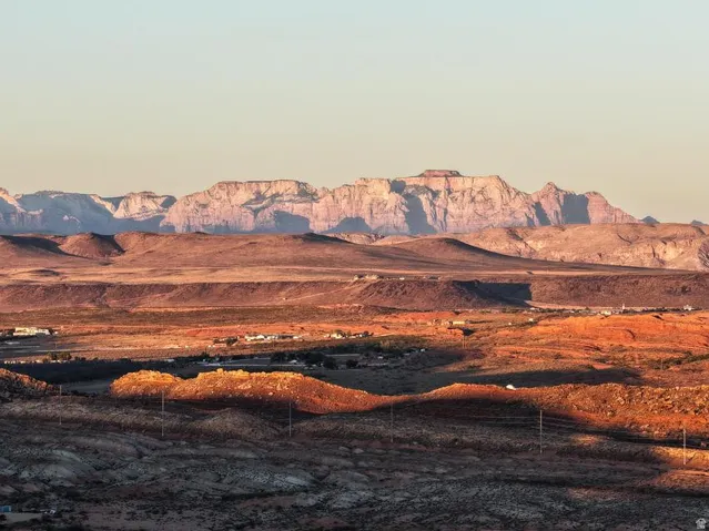 Expansive desert landscape featuring distant mountain ranges and scattered structures