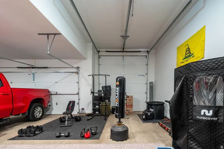 Spacious garage featuring epoxy-coated flooring, overhead storage systems, and ample wall space for equipment organization