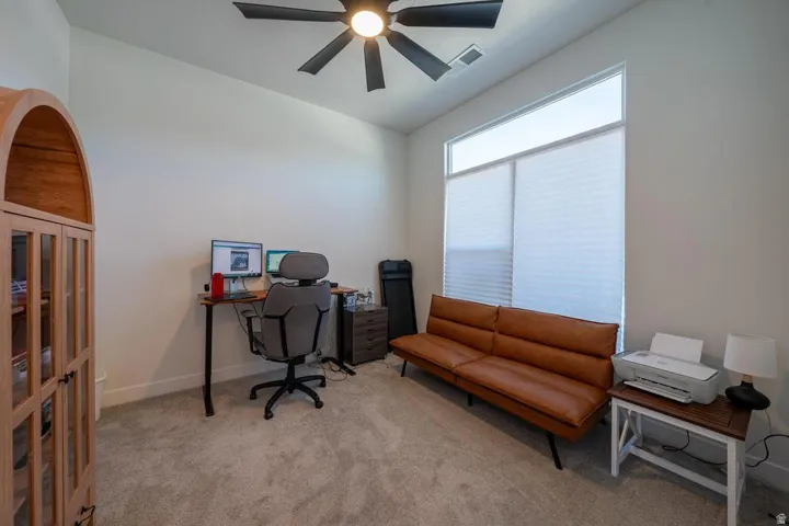 Carpeted room featuring a ceiling fan with integrated lighting, a tall window with cellular shades, and white baseboards