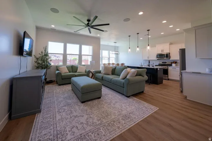 Open-concept living area featuring a gray upholstered sectional, wood-finish flooring throughout, and a coordinating area rug