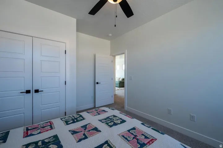 Spacious bedroom featuring neutral wall finishes, ceiling fan with integrated lighting, dual closets with six-panel doors, and hard-surface flooring throughout