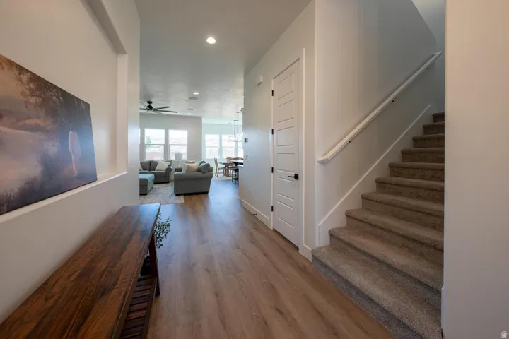 Entryway featuring wood-finish flooring, a white five-panel interior door, and a carpeted staircase with a white handrail