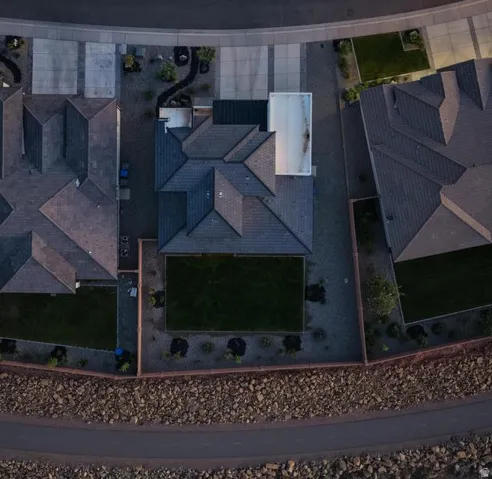 Aerial view showcasing a contemporary residence with multi-pitched architectural rooflines featuring dark shingles and geometric design elements