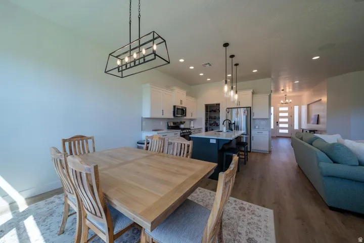 Open-concept living space featuring wood-finish flooring, recessed lighting, and a contemporary kitchen with white cabinetry and an island