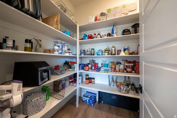 Spacious pantry featuring floor-to-ceiling white cabinetry with multiple shelves, built-in countertop workspace with integrated appliances, and ample storage for pantry staples and kitchen equipment