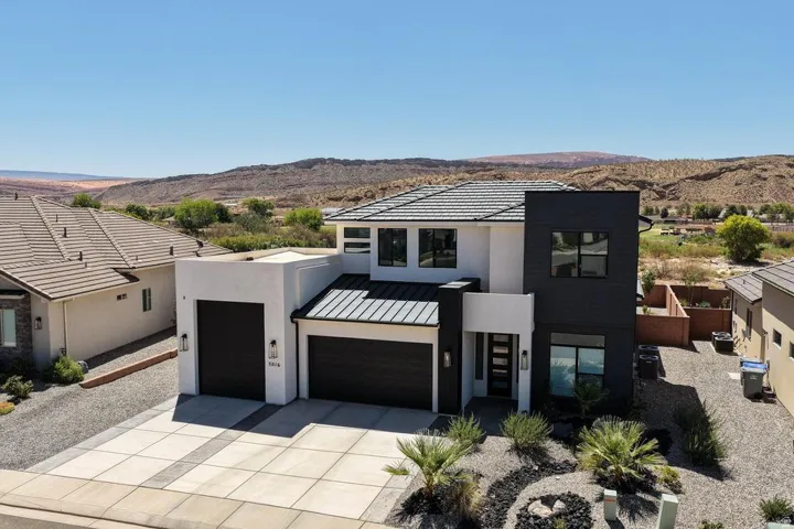 Modern desert architecture featuring a white stucco and dark panel facade with a flat roofline