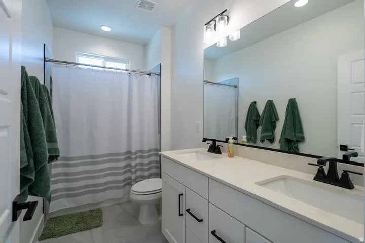 Dual vanity with stone-finish countertop, matte black fixtures, and integrated sinks