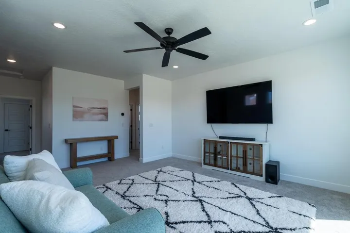 Spacious living area featuring a ceiling fan, recessed lighting, and light-toned carpeting