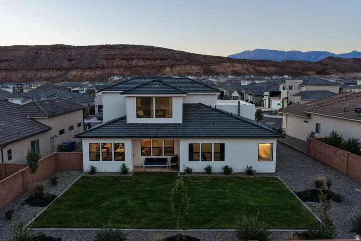 Modern residence showcasing a clean-lined architectural design with a striking white exterior, expansive glazing across the rear elevation, and a flat roof punctuated by a geometric upper-level pavilion