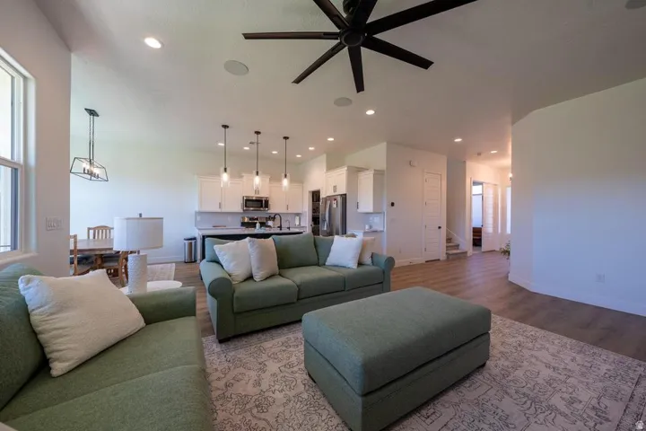 Open-concept living space featuring wood-finish flooring, recessed lighting, and a dark-toned ceiling fan