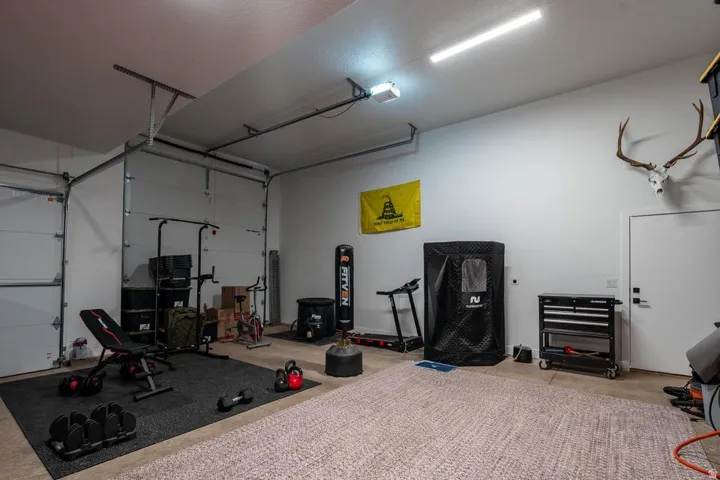 Spacious garage featuring two overhead doors, a side access door, and overhead lighting