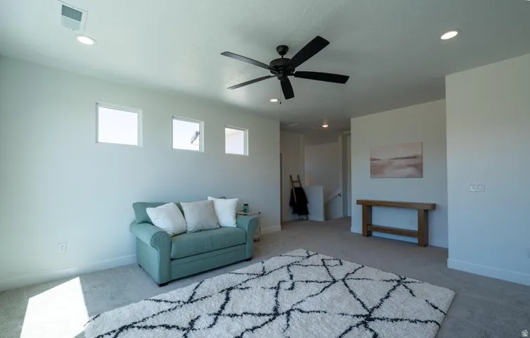 Spacious room featuring light-colored walls, recessed ceiling lights, and a black ceiling fan
