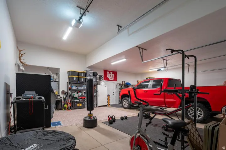 Spacious garage with high ceilings, multiple linear light fixtures, and a textured concrete floor