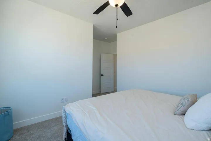 Carpeted room featuring a ceiling fan with light fixture, white walls, and white trim