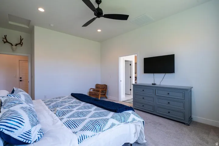 Spacious primary bedroom featuring neutral wall finishes, carpet flooring, and abundant natural light from multiple windows