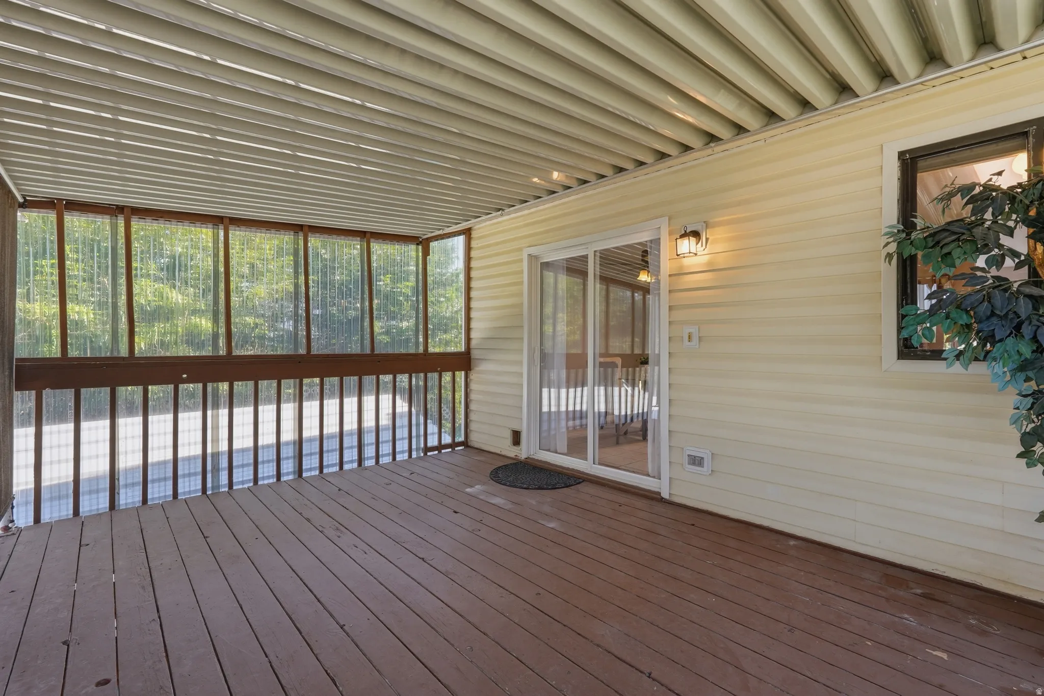 Spacious covered deck featuring composite decking, metal railings with vertical balusters, and a corrugated metal ceiling