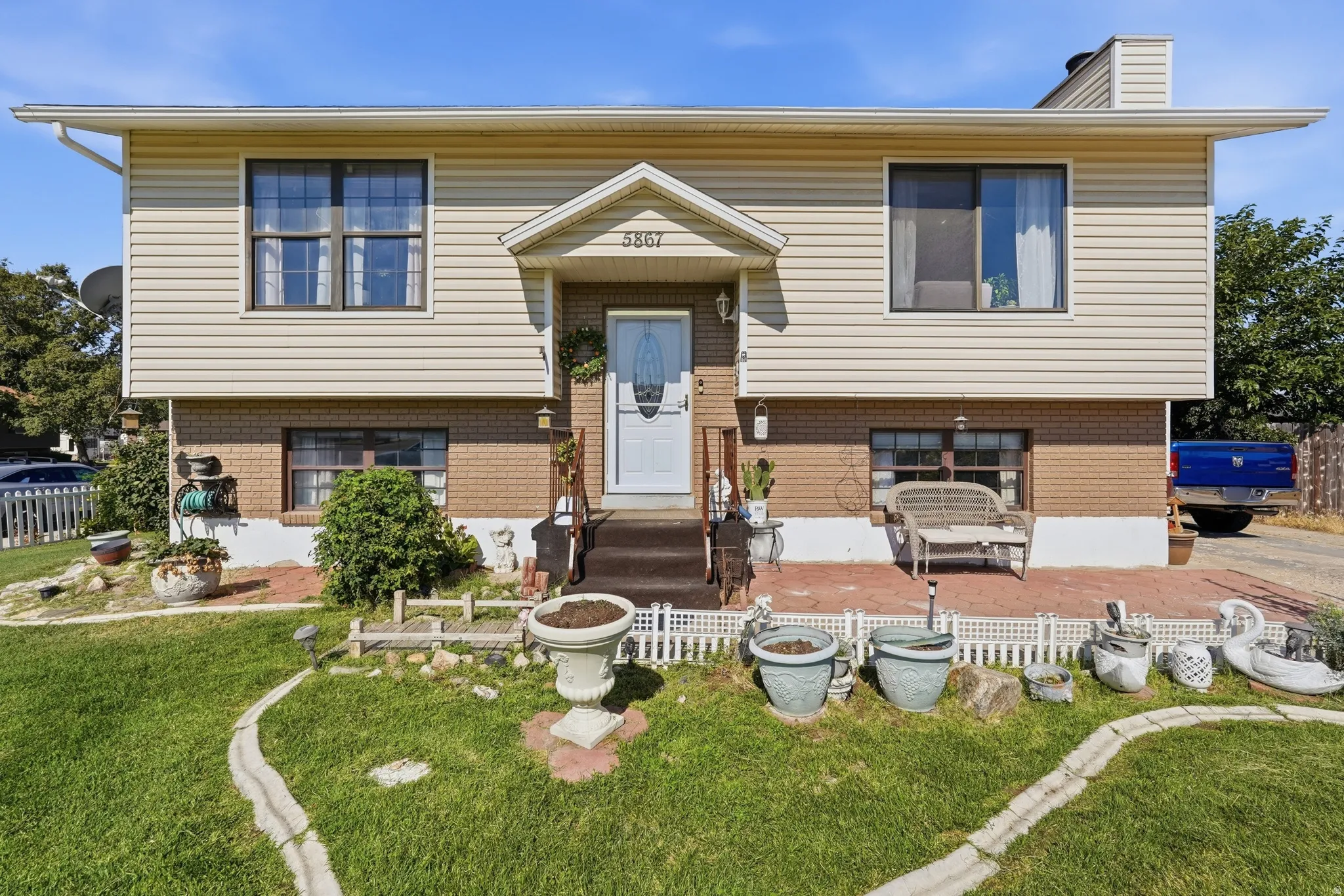 Split-level home featuring a brick and vinyl exterior with a centered entry portico