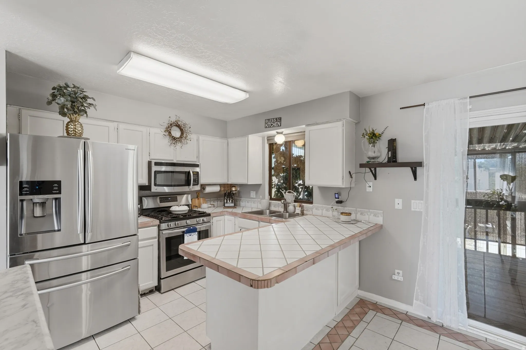 Bright, open kitchen featuring stainless steel French-door refrigerator, built-in microwave, and electric range