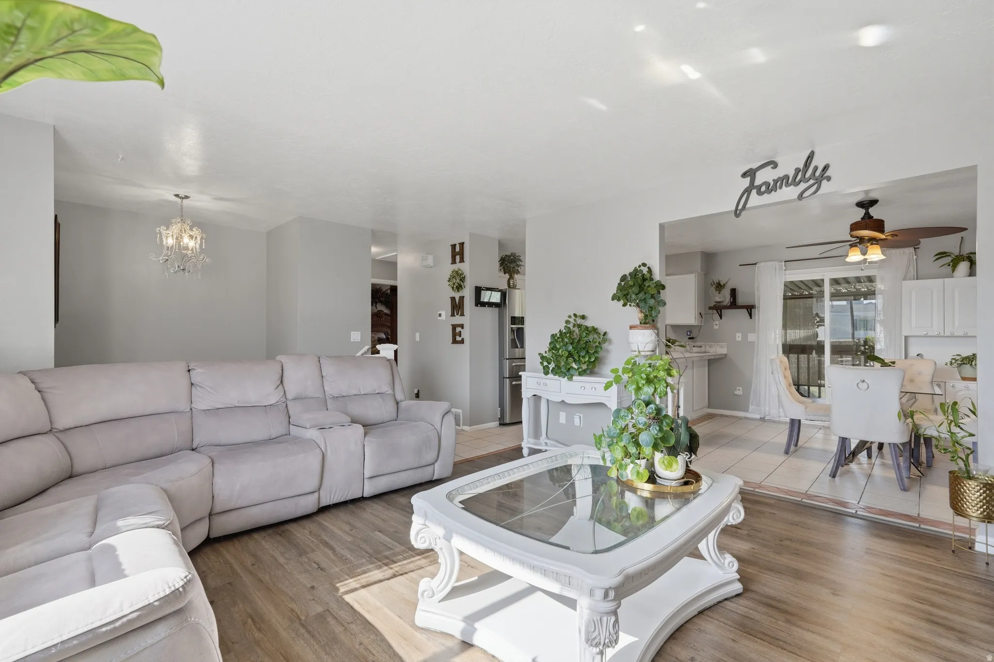 Bright, open living area featuring a spacious sectional sofa, wood-finish flooring throughout, and abundant natural light from multiple windows