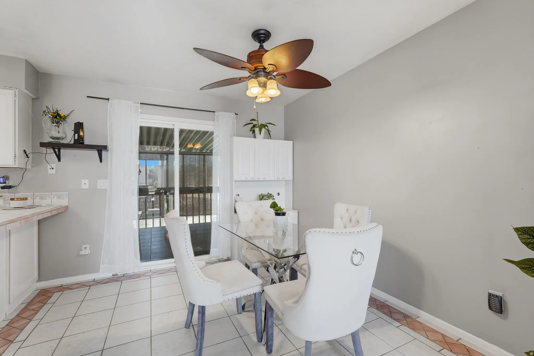 Bright dining area showcasing tile flooring, a ceiling fan with integrated lighting, and glass French doors opening to an outdoor space