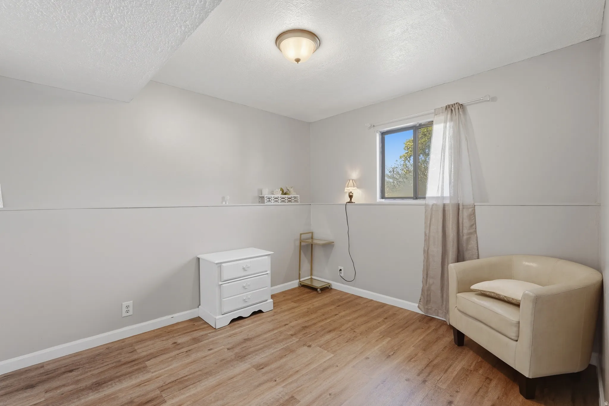 Bright bedroom featuring wood-finish flooring, recessed ceiling lighting, and large window with natural light