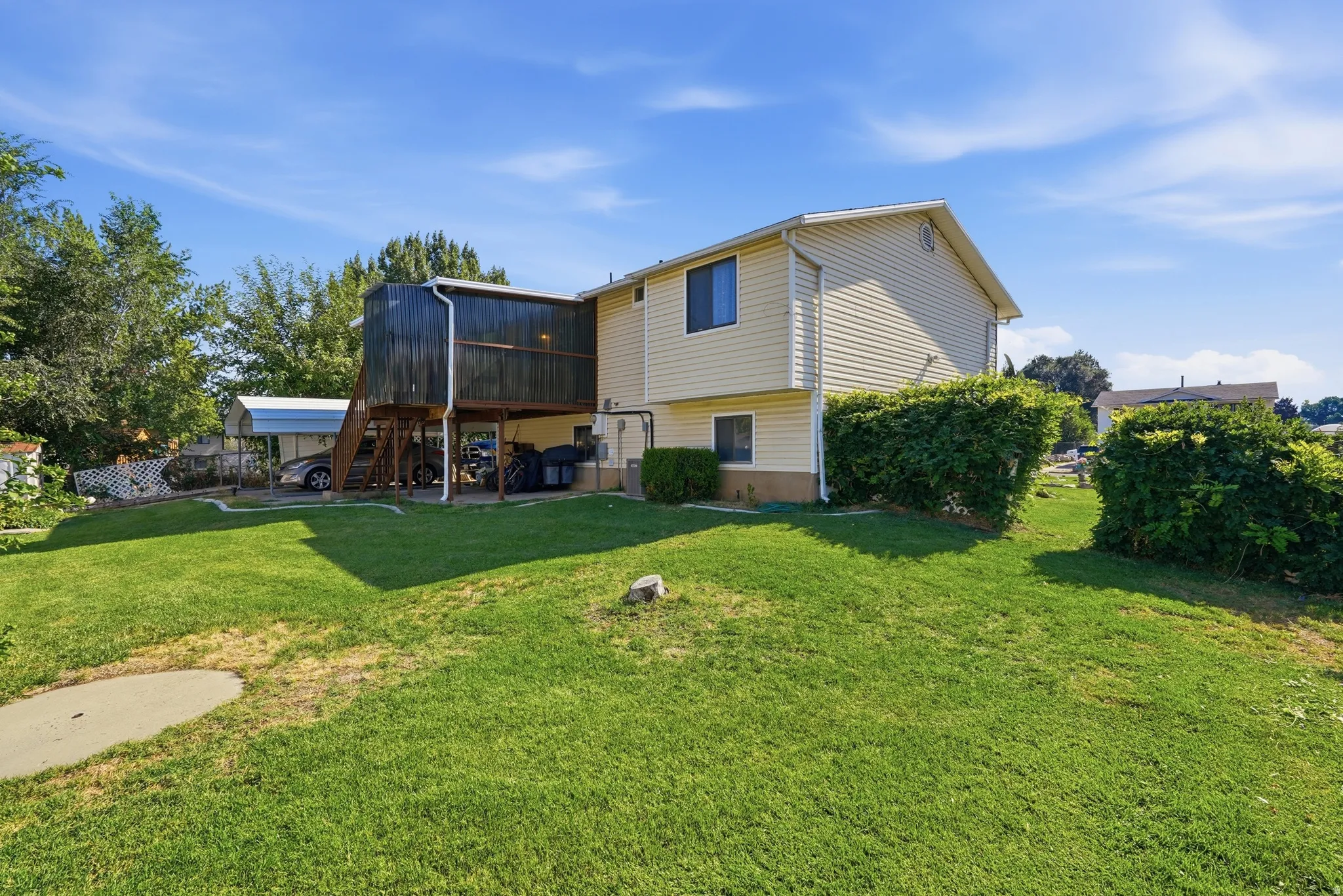 Spacious  home with vinyl siding and multi-level deck featuring covered entry and wooden stairs