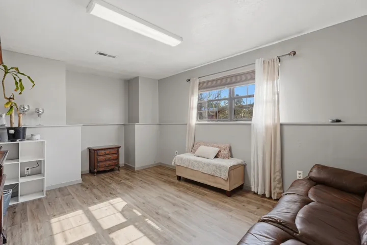 Bright room featuring light wood-finish flooring, neutral gray walls with wainscoting, and a window with natural light