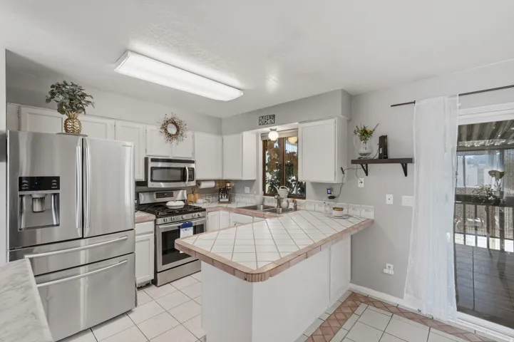 Bright, open kitchen featuring stainless steel French-door refrigerator, built-in microwave, and electric range