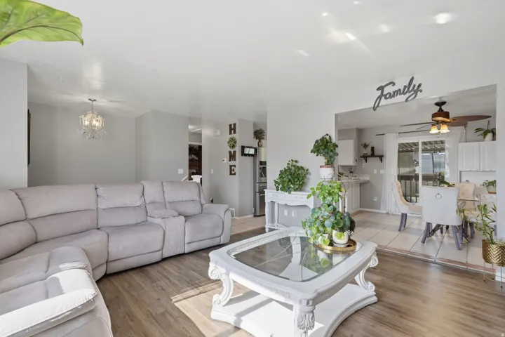 Bright, open living area featuring a spacious sectional sofa, wood-finish flooring throughout, and abundant natural light from multiple windows