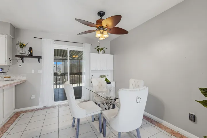 Bright dining area showcasing tile flooring, a ceiling fan with integrated lighting, and glass French doors opening to an outdoor space