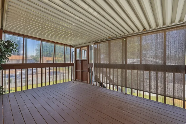 Screened porch featuring wood-finish flooring, a metal ceiling, and roll-down sun shades