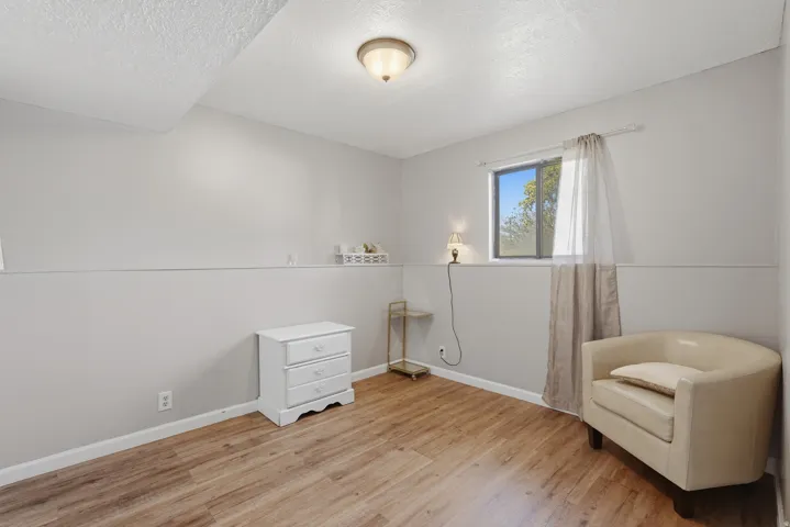 Bright bedroom featuring wood-finish flooring, recessed ceiling lighting, and large window with natural light