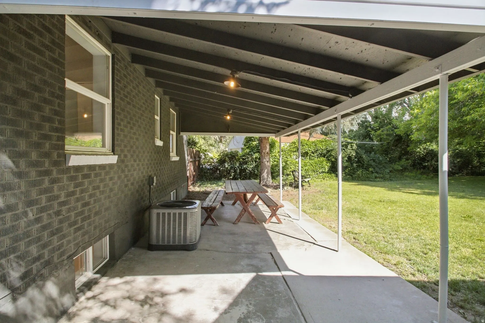 Covered concrete patio extending along a brick exterior