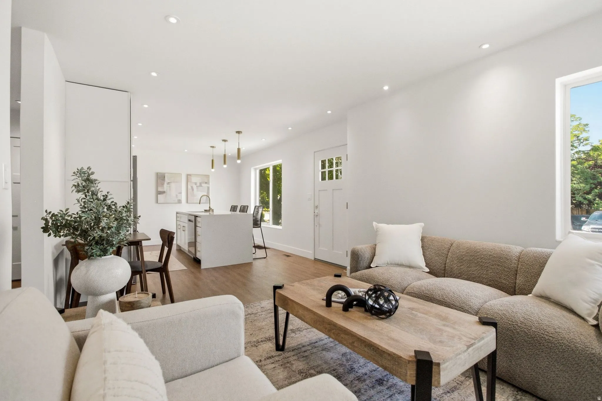 Bright, open living space featuring hardwood flooring, recessed ceiling lighting, and large windows with natural light