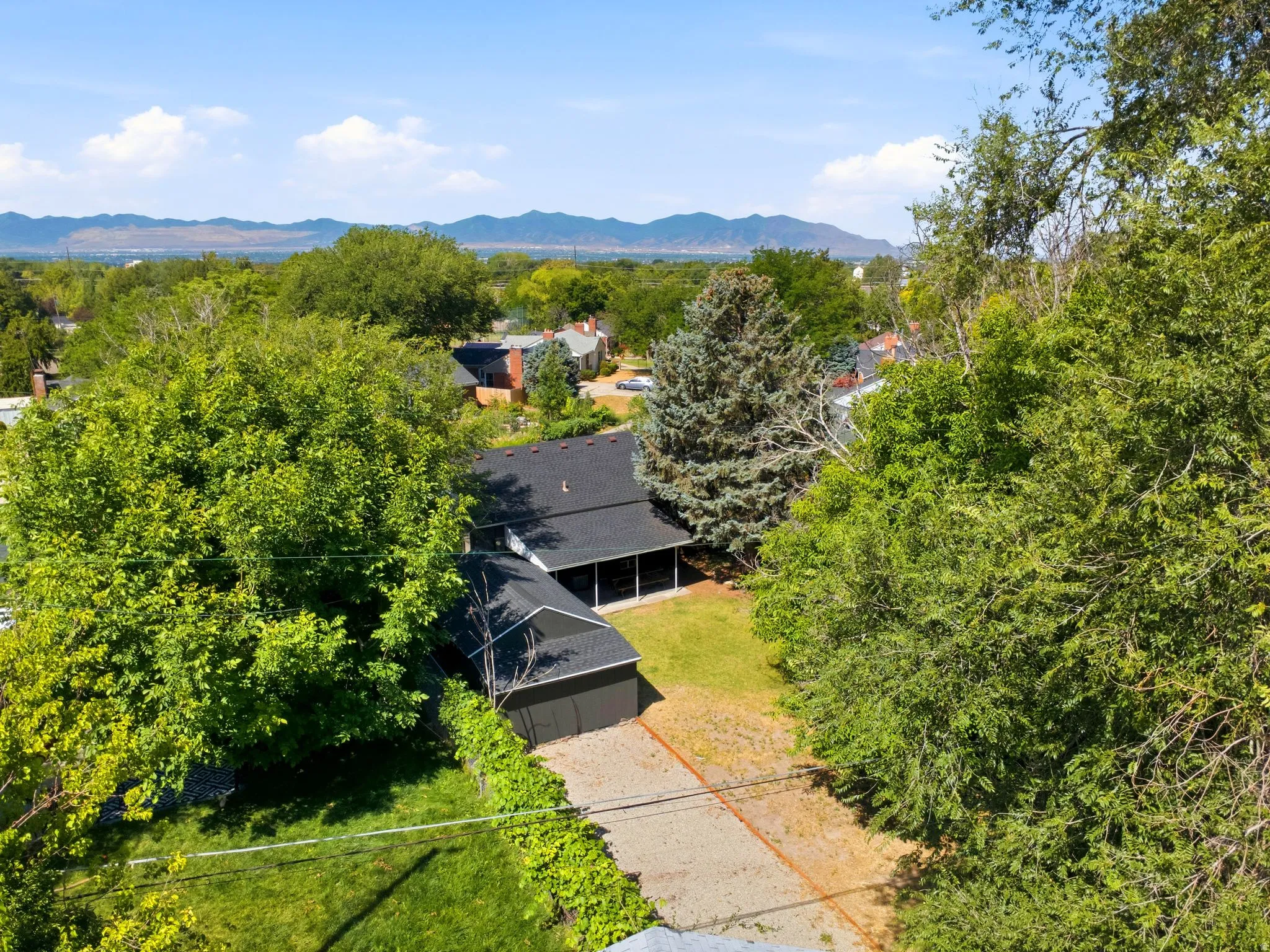 Aerial perspective showcasing a single-story residence with a dark shingled roof, an attached garage, and a screened porch