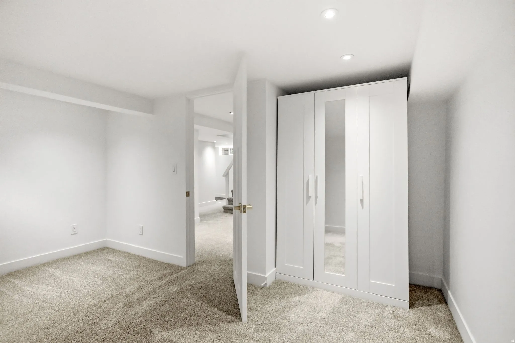 Room featuring light-colored carpeting, white baseboards, and bright white walls