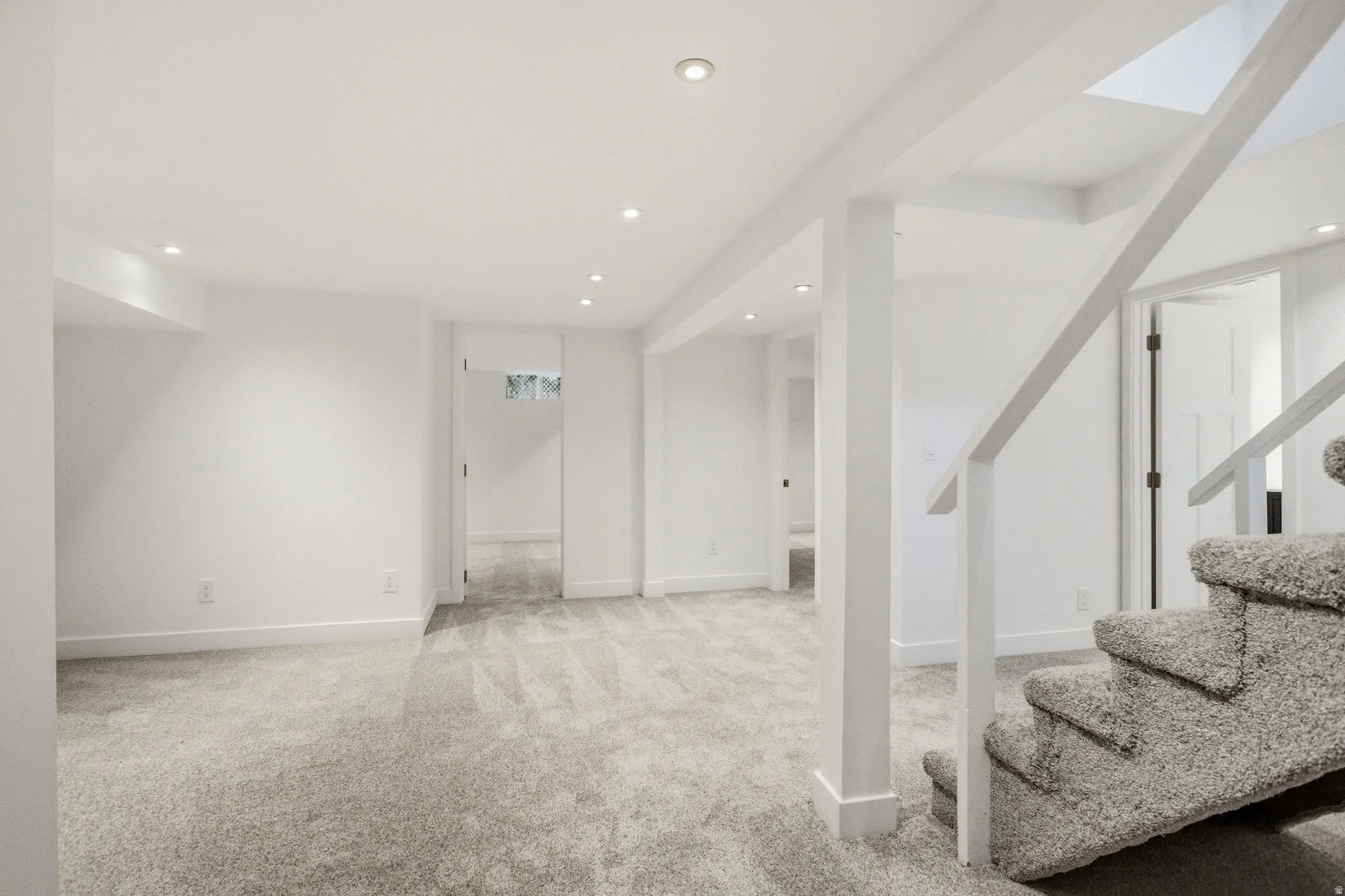 Expansive basement featuring open-concept layout with plush carpeting, recessed ceiling lights, and support columns