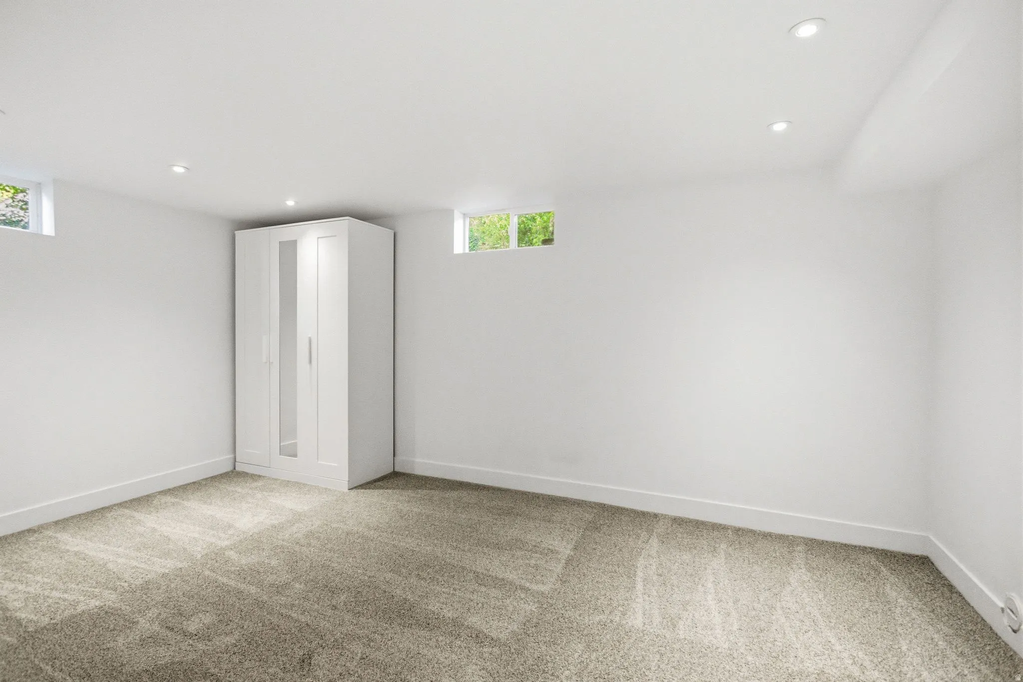 Expansive room with neutral carpeting and bright white walls