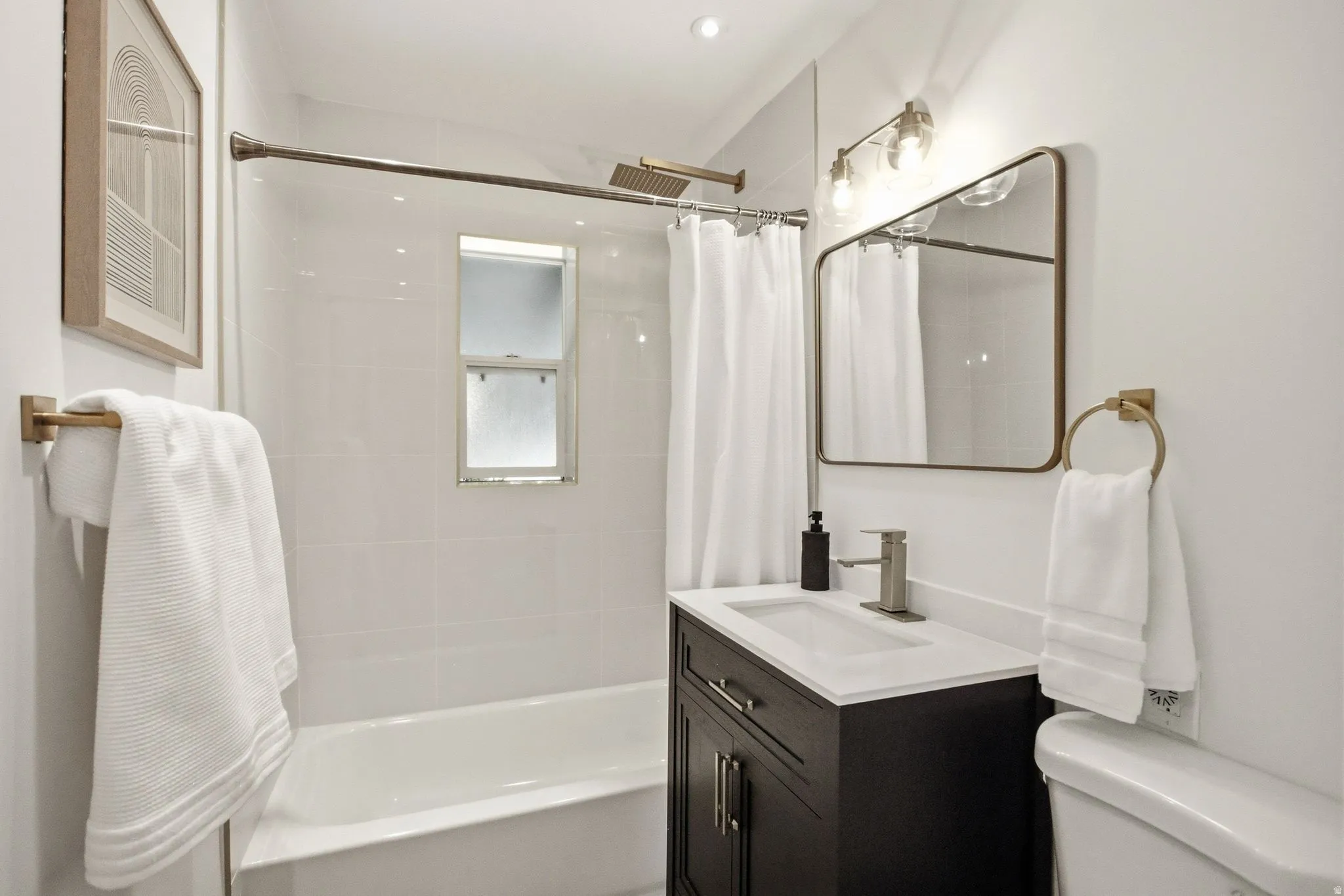 Bathroom featuring a white subway tile tub surround, dark wood-finish vanity with a white countertop, and brushed nickel fixtures
