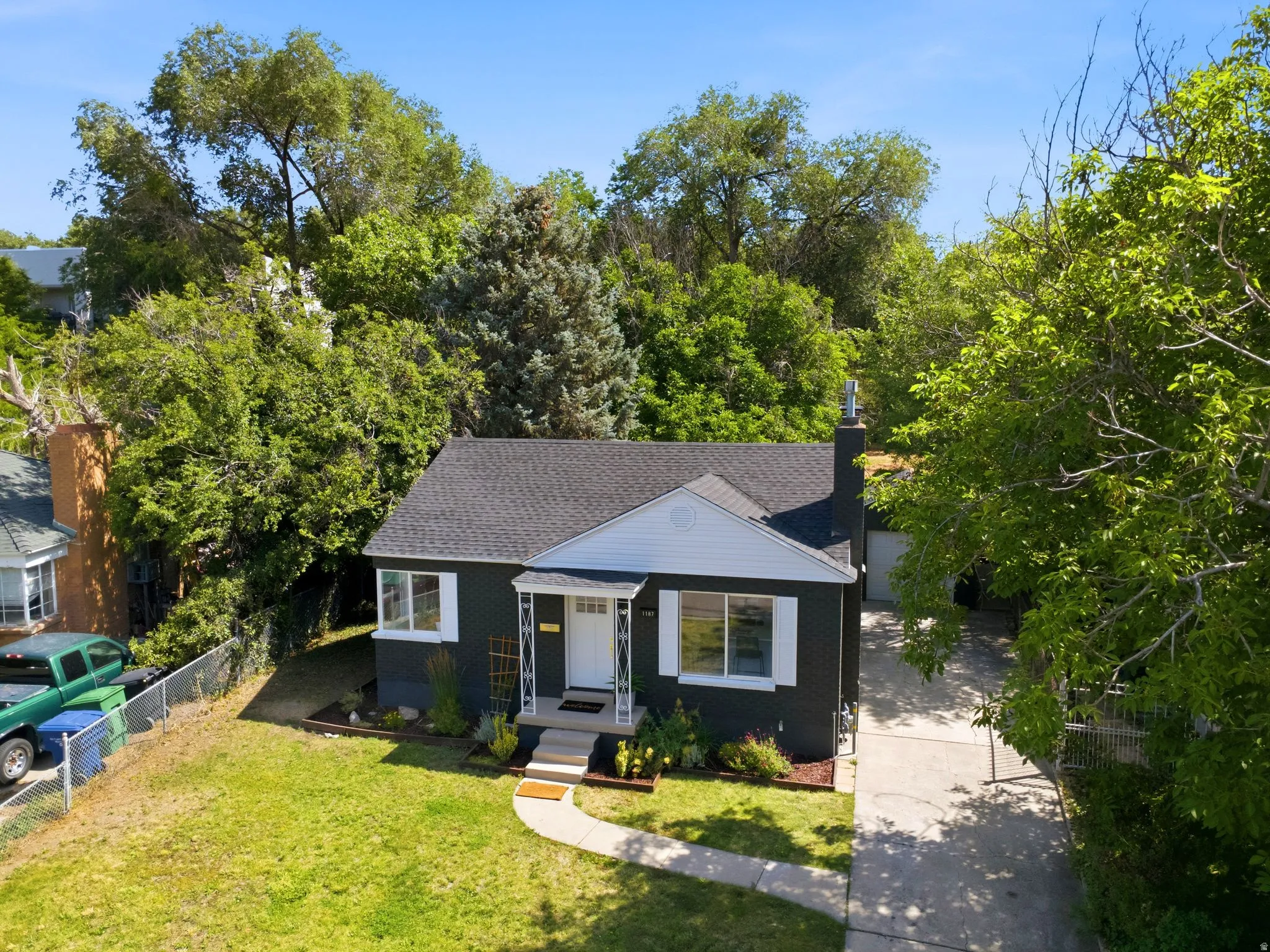 Classic cottage-style home featuring a freshly reshingled roof, black exterior siding, and a covered front porch with white trim detailing