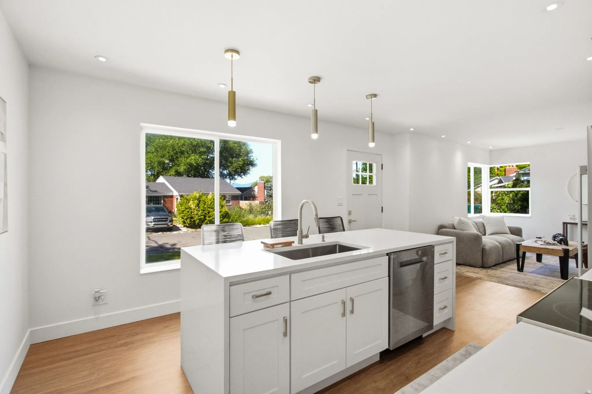 Contemporary kitchen island featuring a stainless steel sink with a high-arc faucet, quartz countertop, and white shaker cabinetry